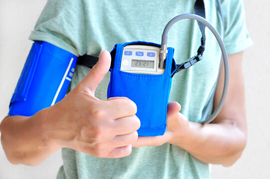 Woman wearing holter monitor device for daily monitoring of an electrocardiogram. Health care and disease prevention.Woman showing thumb up - the result is good
