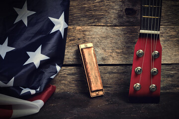 Flag of the United States of America, harmonica and guitar neck on an old wooden background.