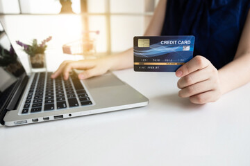 Closeup hand of women is holding a credit card and using computer notebook for shopping online.