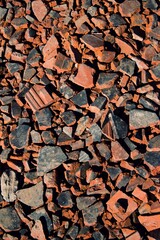 Broken old roof tiles. These shards are used to repair forest roads.Detail of many pieces of used roof tiles. Roof tiles serve as a filling for holes on forest and field roads.