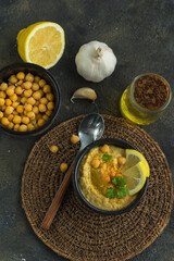 Chickpea puree hummus , lemon, garlic and olive oil on a dark background close-up