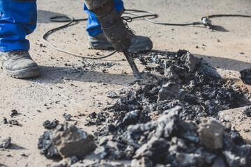 Process of road repairing works with jackhammer, builder worker with  pneumatic hammer and drill equipment breaking asphalt pavement and concrete at construction site