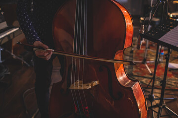 Concert view of a contrabass violoncello player with vocalist and musical during jazz orchestra band performing music, violoncellist double-bass player, cello player performing jazz music on stage