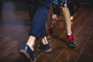 Fototapeta na wymiar Dancing shoes of young couple dance retro jazz swing dances on a ballroom club wooden floor, close up view of shoes, female and male, dance lessons