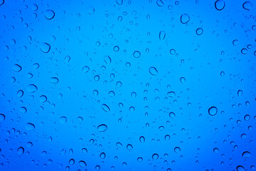 Drops of water on a blue glass, abstract blue background.