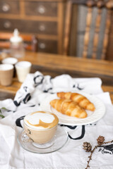 croissants on a plate with cappuccino on the background of a tree