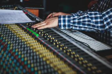 Sound editor engineer working at studio with mixing panel, mixing music and sound, stage sound...