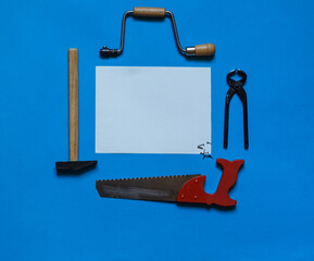 Carpentry tools on an aquamarine background with a white lettering sheet in the center,top view with space