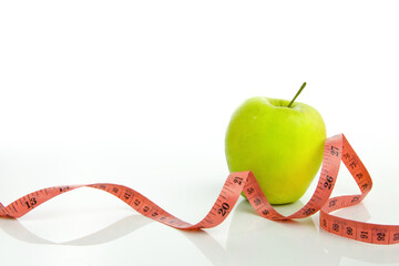 Green apple with tape measure on a white background. Diet and weight loss concept