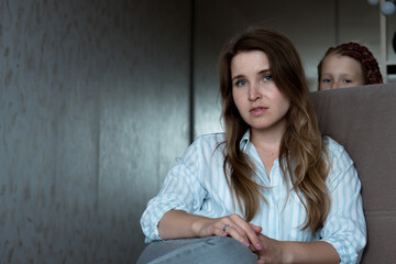 young unhappy tired woman with little girl at home. mother and daughter relationships.