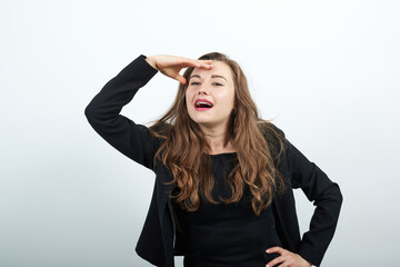Fototapeta premium Young Attractive Woman Brunette In In Black T-Shirt And Sweater On White Background, Female Waiting For A Man Looks, Holds Hand To Her Forehead. The Concept Of People Who Missed, Expected