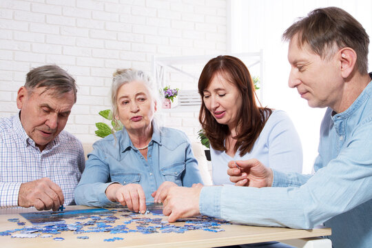 Senior couple solving jigsaw puzzle together with family at home.