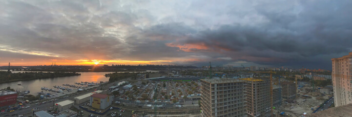 Mobile photography of panoramic Kyiv view located in Ukraine from the twenty second floor, as arial view on right side of Kyiv and Dnipro river from Pozniaky with sunset and cloudy sky in urban city