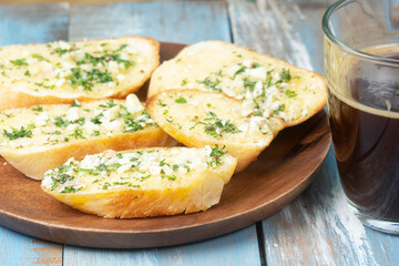 Garlic bread on the wooden plate with black coffee