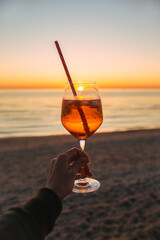 Girl Holding Glass of Drink on Beach at Beautyfull Romantic Sunset. Glass and Hand Close Up