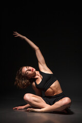 Young girl doing yoga on a black background