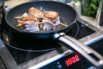 meat medallions in bacon are fried in a pan