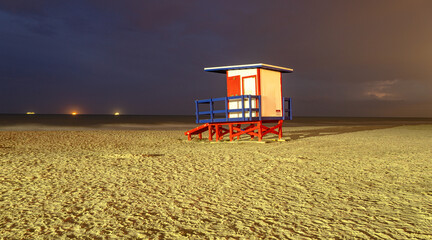 Fototapeta premium Lifeguard tower at night. A beautiful beach in Florida. Miami nightlife. Beautiful Miami Beach sand without people.