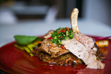 grilled pork ribs with hot sauce on potatoes served on a red plate