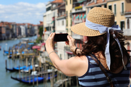 woman with straw hat while takes pictures of Venice