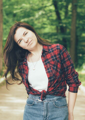 
Woman in the forest looks in frame and smiles.