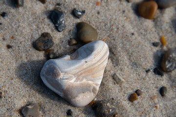 Fototapeta na wymiar gemaserter Stein am Strand, im Sand liegend