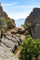 Mountain trail among the rocks against the backdrop of mountains and blue sky