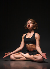 Young girl doing yoga on a black background