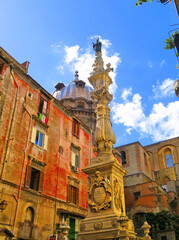 Naklejka premium Napoli, Piazza Riario Sforza square, Obelisk of San Gennaro column and old buildings and dome in background. Naples Italy 