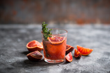Old-fashioned cocktail with blood oranges and thyme on the rustic background. Selective focus. Shallow depth of field.
