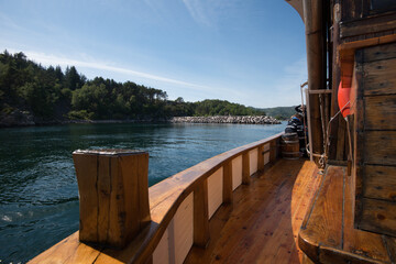 Railing of an old wooden fishing boat passing through a narrow sound.