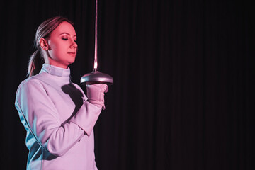 Fencer in fencing suit holding rapier isolated on black