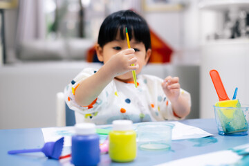 Toddler girl holding paint brush. . Asian toddler girl is painting water color. toddler activity at home. - 353655587