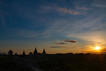 Ancient castle with towers lit by the setting sun against a blue sky