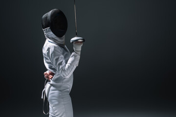 Side view of fencer holding rapier isolated on black with copy space