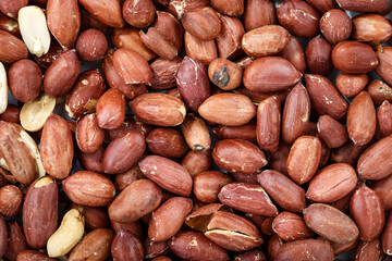 peeled peanuts scattered as a background. Peanut texture is clearly visible..