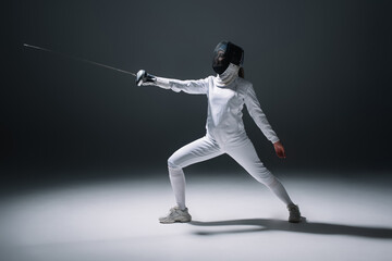 Fototapeta na wymiar Fencer training with rapier on white surface on black background