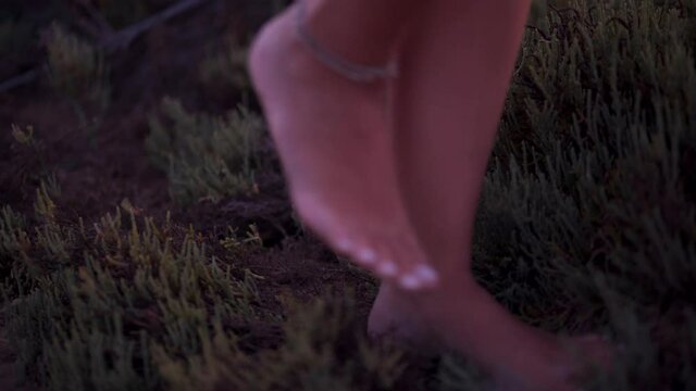 Close-up of young woman with anklet walking barefoot in nature