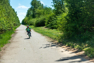Obraz premium Boy on bicycle at summer asphalt road. Kid cycling outdoors. Summer sport activity concept. Soft focus