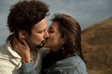 Lovers passionately kiss and hug each other in the sunlight. Stylish couple kisses each other with...