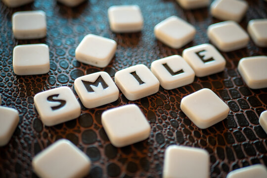 Piezas con letras de un juego de mesa formando la palabra "smile"