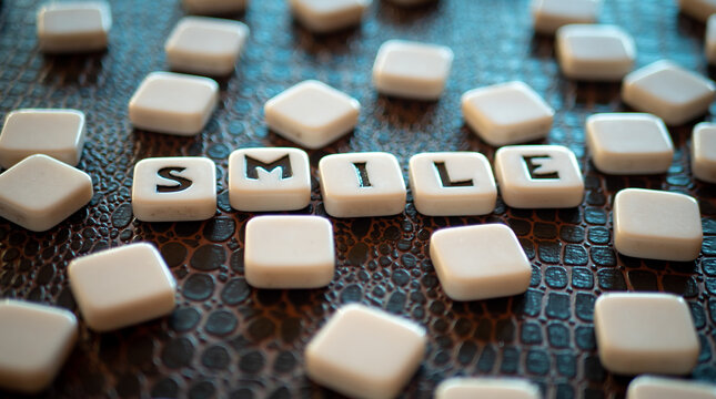 Piezas con letras de un juego de mesa formando la palabra "smile"