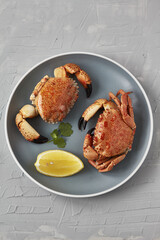 Seafood. Boiled crabs on plate served with lemon, herb. 
Top view
