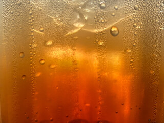 Defocused glass photo with brown Soft drink And water droplets and ice is inside Feels fresh and...