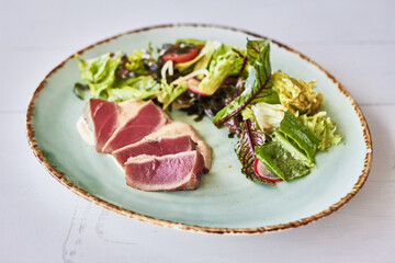 Salad with pieces of medium-rare grilled  tuna and   fresh mix salad on a plate