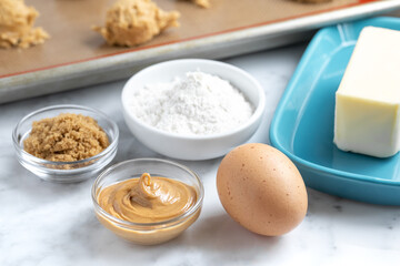 Peanut butter cookie baking ingredients with dough ball in the background
