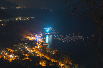 Night city. View of the village from the top of the mountain, streets and lights, a bay with boats. Travel and vacation concept in Italy, Nerano.