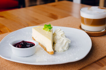 Slice of cheesecake on a plate and cappuccino