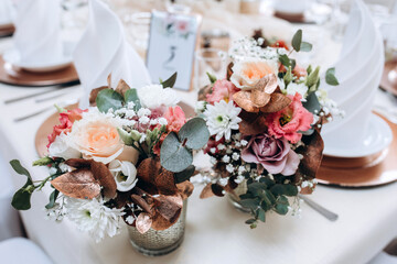 Wedding flowers on the banquet table. Table decoration. Table setting and decorations.