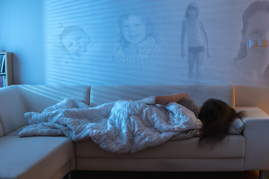 Woman sleeping on the sofa, with images from her childhood projected on the wall